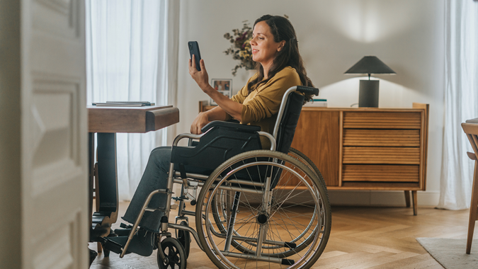 A young woman looks at her phone while sitting in a wheelchair